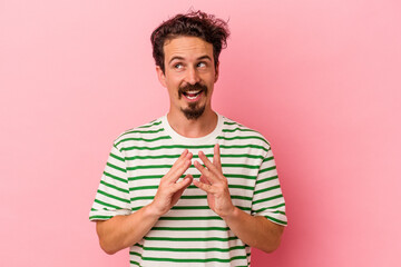 Young caucasian man isolated on pink background making up plan in mind, setting up an idea.