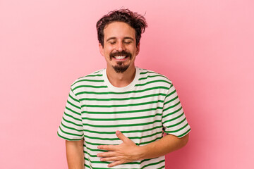 Obraz premium Young caucasian man isolated on pink background touches tummy, smiles gently, eating and satisfaction concept.
