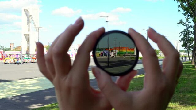 View of a beautiful multi-colored building through round tinted glass. Women's hands twist the ND filter and it becomes transparent