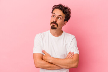 Young caucasian man isolated on pink background dreaming of achieving goals and purposes