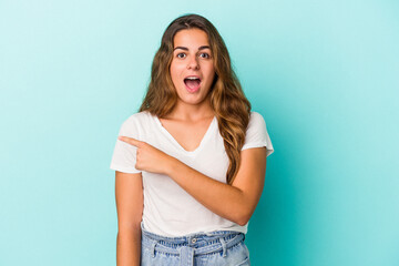 Young caucasian woman isolated on blue background  pointing to the side