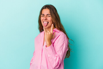 Fototapeta premium Young caucasian woman isolated on blue background showing rock gesture with fingers
