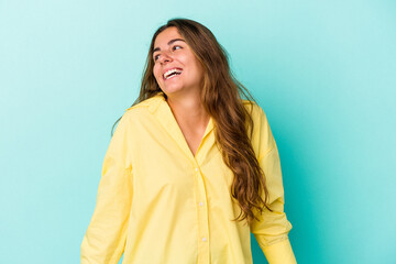 Obraz premium Young caucasian woman isolated on blue background laughs and closes eyes, feels relaxed and happy.