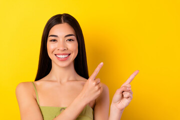 Photo of pretty cheerful filipino person indicate fingers empty space isolated on yellow color background