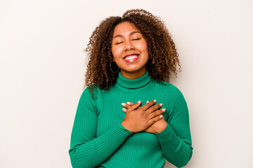 Young African American woman isolated on white background laughing keeping hands on heart, concept of happiness.