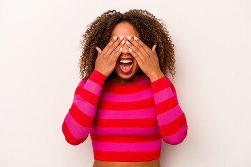 Young African American woman isolated on white background covers eyes with hands, smiles broadly waiting for a surprise.