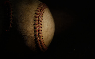 Old used baseball ball closeup, isolated on dark black background with copy space.