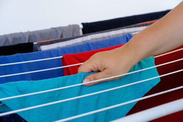 close-up of wet laundry hanging and drying on a wire room dryer, home chores concept, cleaning clothes, proper washing of cotton colored fabrics, selective focus at shallow depth of field