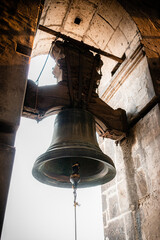 Obraz premium High contrast low, angle backlit photograph in the vertical format of one of the bells cast in copper, bronze, and tin in 1578 and its pole tied to a rope in the Metropolitan Cathedral of Mexico