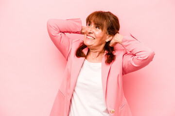 Middle age caucasian woman isolated on pink background feeling confident, with hands behind the head.