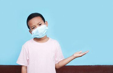 Asian kid wearing surgical mask with hand showing for wording edit in work of Covid 19