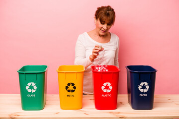 Middle age woman recycling isolated on pink background