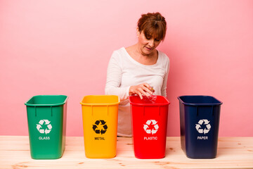 Middle age woman recycling isolated on pink background