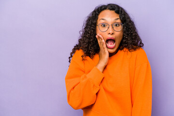 Young hispanic woman isolated on purple background shouts loud, keeps eyes opened and hands tense.