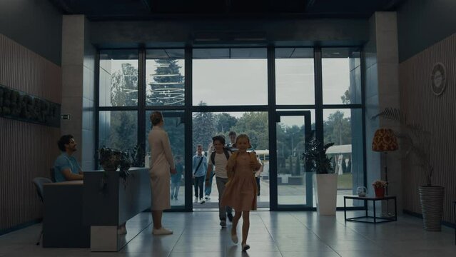 Group Teen Children Entering In School Building. Smiling Teacher Welcome Pupils.