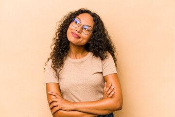 Young hispanic woman isolated on beige background dreaming of achieving goals and purposes