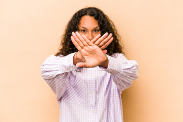 Young hispanic woman isolated on beige background doing a denial gesture