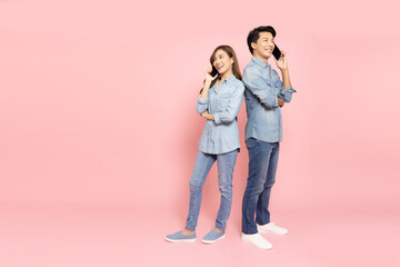 Portrait of young smiling Asian couple talking with mobile phone isolated on pink background, Asian Thai model