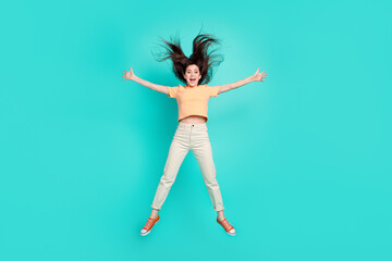 Full size portrait of satisfied sportive lady raise open arms jumping isolated on turquoise color background