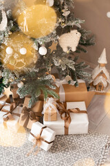 Wrapped gifts under the Christmas tree in a bright interior with garland lights in bokeh.
