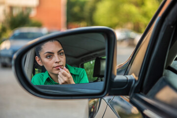 Fototapeta na wymiar Beautiful young girl applying makeup while driving a car. Risky driving.