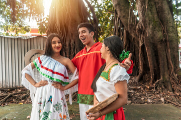 Latino male teenager in traditional clothing with two girls chatting outdoors