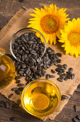 Sunflower oil and sunflower seeds on traditional rustic wooden background. Organic and eco food concept. Healthy food and fats.