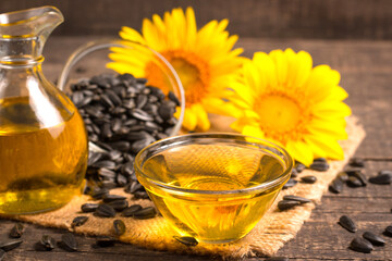 Sunflower oil and sunflower seeds on traditional rustic wooden background. Organic and eco food concept. Healthy food and fats.