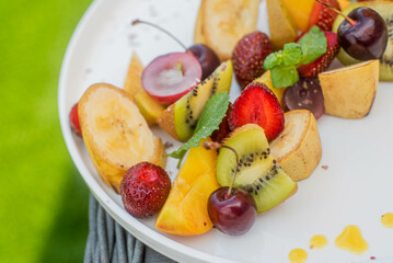 Fruit plate. Kiwi, bananas, cherries, strawberries and peaches on a plate