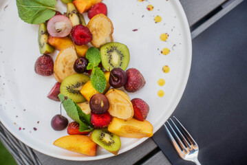 Fruit plate. Kiwi, bananas, cherries, strawberries and peaches on a plate