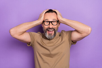 Photo of cheerful excited overjoyed man touch head can't believe he won money prize isolated on purple color background