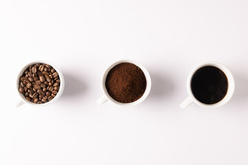 Image of three cups full of ground coffee, coffee beans and coffee on white background