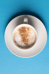 Image of white cup of coffee with milk on blue background