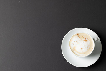Image of white cup of coffee with milk on black background