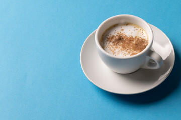 Image of white cup of coffee with milk on blue background