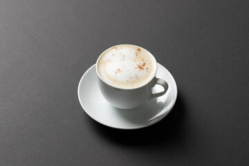 Image of white cup of coffee with milk on black background