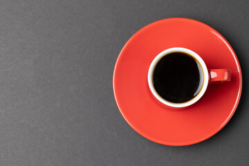 Image of red cup of hot black coffee on black background