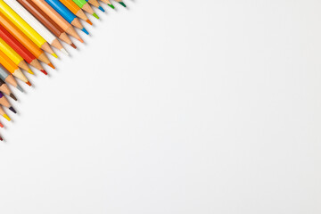 Composition of colorful crayons on white surface with copy space