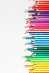 Vertical composition of colorful crayons on white surface with copy space