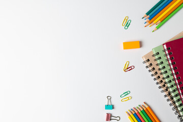 Composition of notebooks, clips and crayons on white surface with copy space