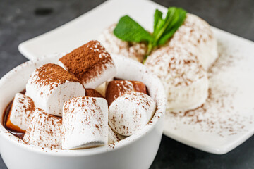 hot chocolate with marshmallows and ice cream balls on a black background