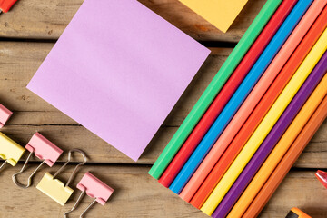 Obraz premium Composition of crayons, post it and clips on wooden surface