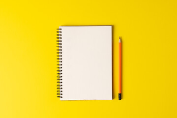 Composition of notebook with copy space and pencil on yellow surface