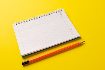 Composition of notebook with copy space and pencil on yellow surface