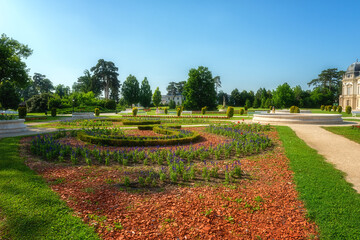 Fototapeta na wymiar Beautiful garden of Festetics Palace with flowers and green grass and trees on a sunny summer day, Keszthely, Zala, Hungary. Outdoor travel background