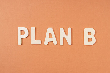 white wooden letters make up the word plan b on a brown background