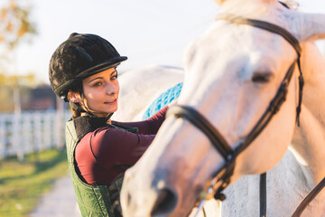 Obraz premium Portrait of a girl preparing her horse for riding.