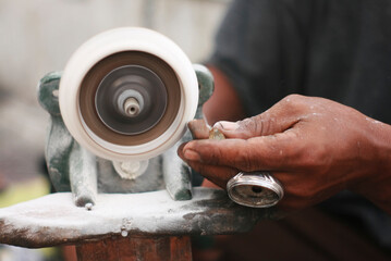 Midsection of man polishing ring in workshop