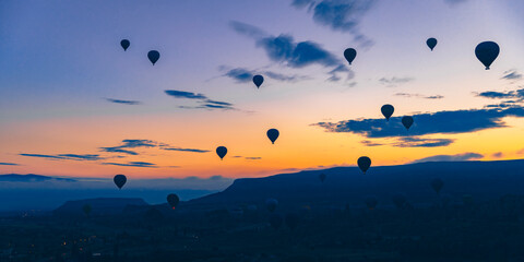 hot air balloons fly at sunrise over the city of Goreme