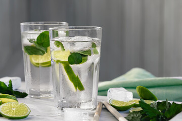 Summer refreshing mojito cocktails with lime and mint on a white wooden tray